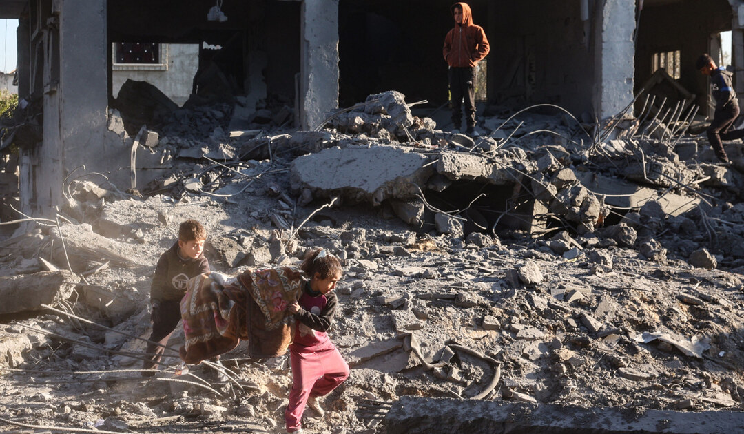 Palestinian children salvage a blanket amid the destruction in the aftermath of an Israeli strike in Gaza. (AFP)